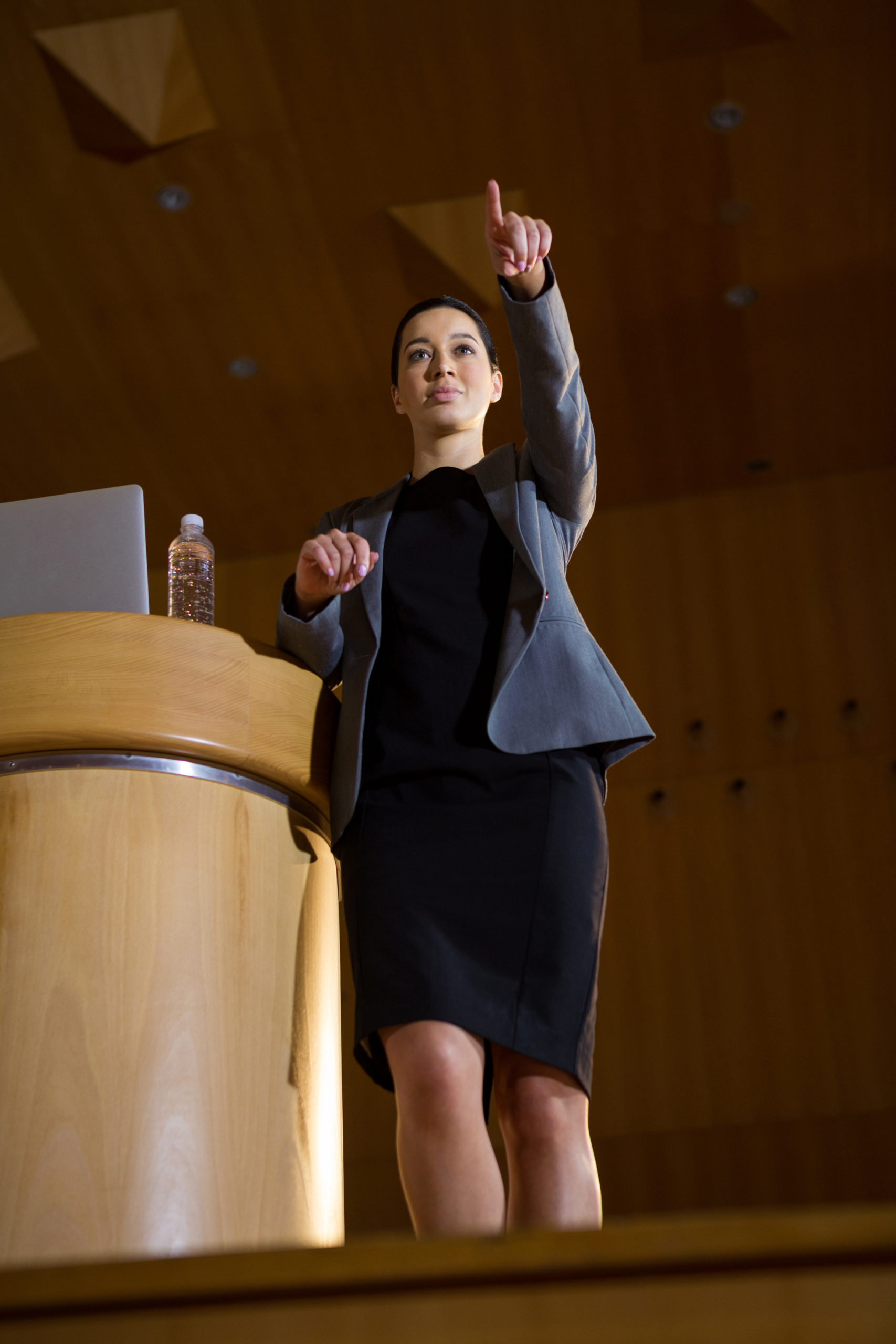 Female business executive pointing while giving a speech at conference center